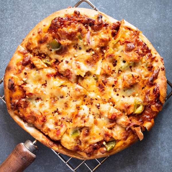A freshly baked Sammy's Italian chicken pizza with melted cheese, green peppers, and red pepper flakes.